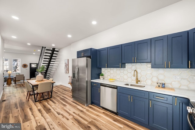 kitchen featuring decorative backsplash, light countertops, blue cabinets, a sink, and stainless steel appliances