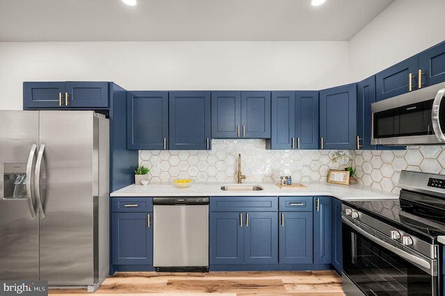 kitchen with appliances with stainless steel finishes, a sink, and blue cabinets