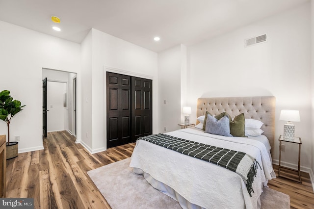 bedroom with visible vents, a closet, wood finished floors, baseboards, and recessed lighting