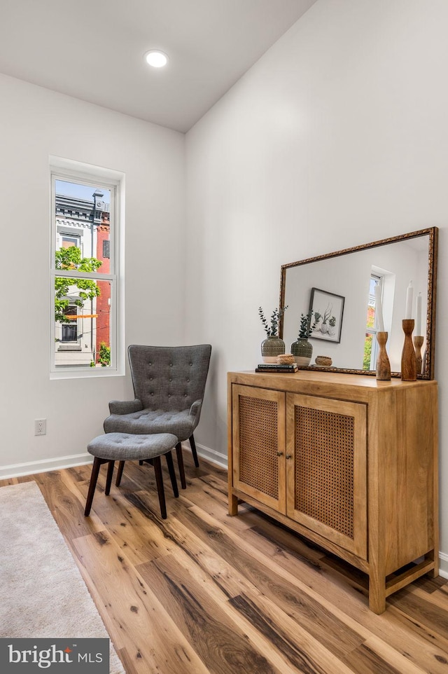 living area featuring baseboards, recessed lighting, wood finished floors, and a healthy amount of sunlight