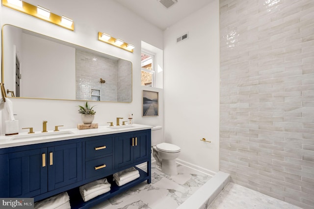 bathroom with toilet, tiled shower, a sink, and marble finish floor