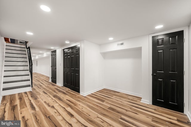 finished below grade area with stairway, light wood-style floors, recessed lighting, and visible vents
