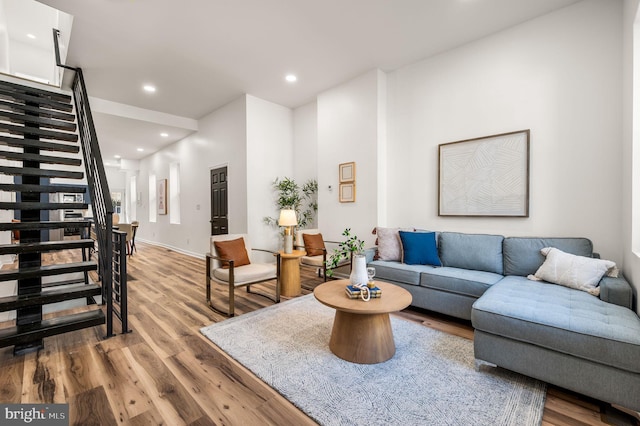 living room featuring recessed lighting, baseboards, wood finished floors, and stairway