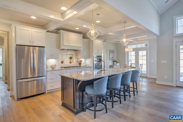 kitchen featuring a breakfast bar, light wood-style floors, an island with sink, white cabinetry, and stainless steel appliances