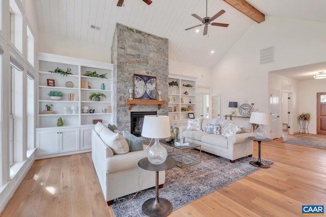 living area featuring high vaulted ceiling, a stone fireplace, light wood-style flooring, a ceiling fan, and visible vents