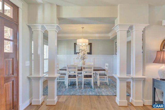 dining space featuring a wainscoted wall, a decorative wall, and light wood-style flooring
