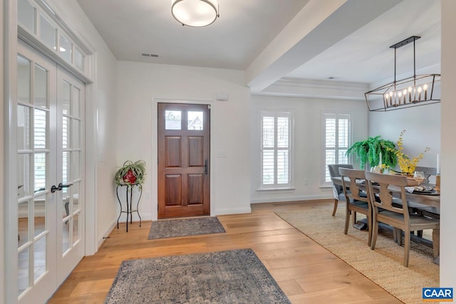 foyer featuring visible vents, light wood-style flooring, a healthy amount of sunlight, and french doors