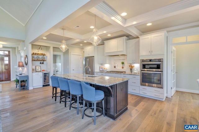 kitchen with crown molding, beverage cooler, an island with sink, a sink, and appliances with stainless steel finishes