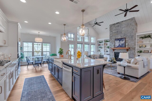 kitchen featuring ceiling fan, a sink, light wood finished floors, stainless steel appliances, and white cabinetry