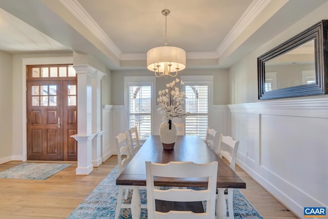 dining space with wainscoting, light wood-style floors, a decorative wall, and a chandelier