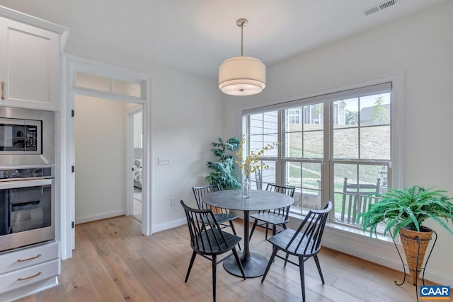 dining space featuring visible vents, light wood finished floors, and baseboards