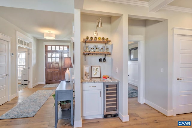 bar with baseboards, a dry bar, light wood finished floors, and wine cooler