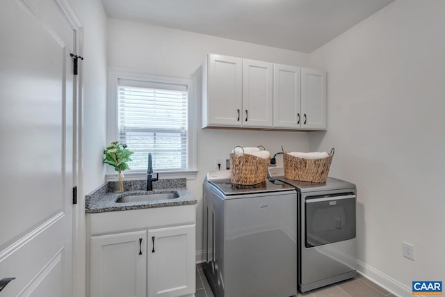 laundry area featuring light tile patterned flooring, baseboards, washer and clothes dryer, a sink, and cabinet space