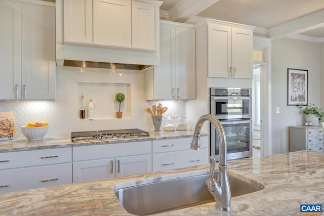 kitchen with appliances with stainless steel finishes, decorative backsplash, a sink, and light stone counters