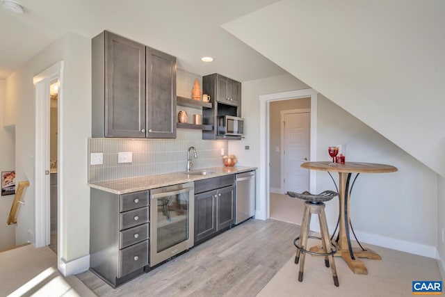 bar featuring wine cooler, light wood-type flooring, a sink, backsplash, and stainless steel appliances