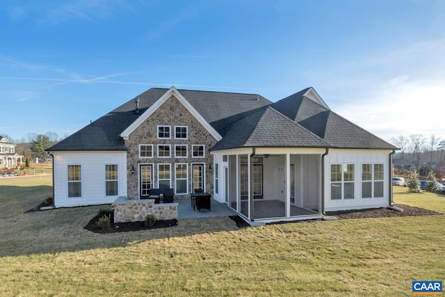 back of property with roof with shingles, stone siding, a sunroom, a lawn, and a patio
