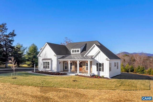 modern farmhouse style home featuring board and batten siding, a standing seam roof, covered porch, and a front lawn
