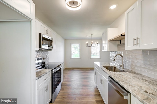 kitchen featuring white cabinets, light stone countertops, a sink, stainless steel appliances, and dark wood-type flooring