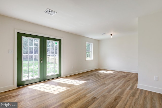 empty room featuring baseboards, visible vents, french doors, and wood finished floors