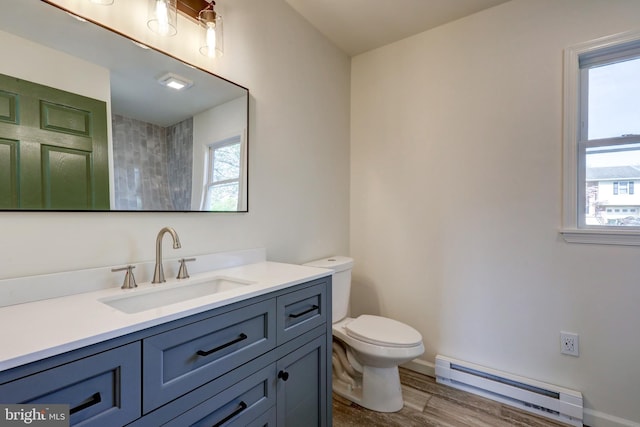 full bath featuring vanity, wood finished floors, toilet, baseboards, and a baseboard heating unit