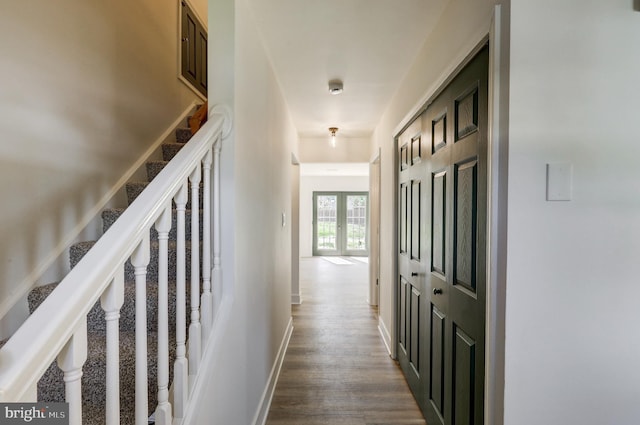 hallway featuring baseboards, stairway, and dark wood-type flooring