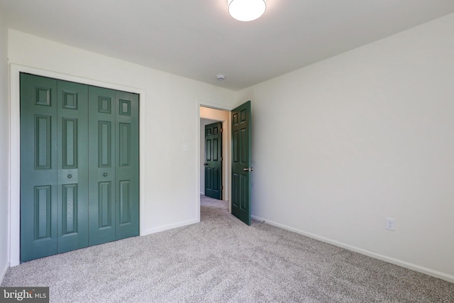 unfurnished bedroom with carpet floors, baseboards, and a closet