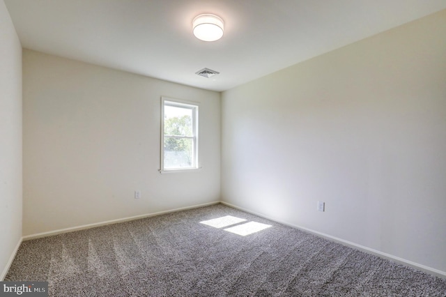 empty room with carpet floors, baseboards, and visible vents
