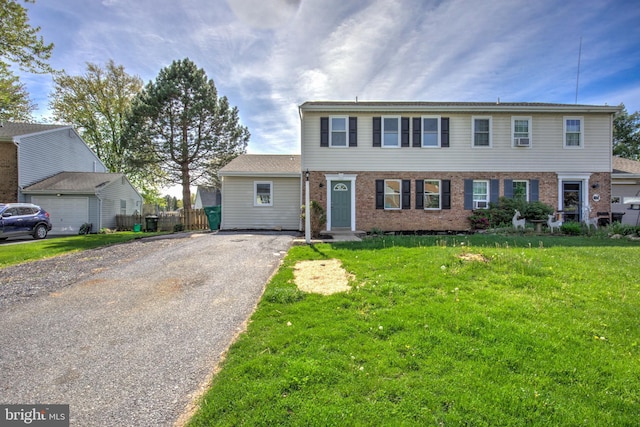 colonial home featuring brick siding, driveway, and a front lawn