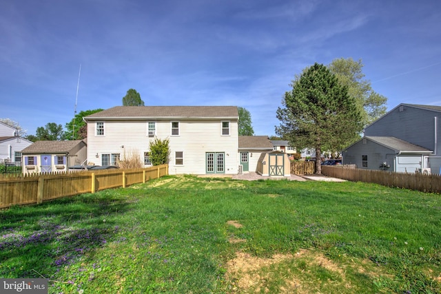 back of house with french doors, a lawn, an outdoor structure, a fenced backyard, and a storage unit
