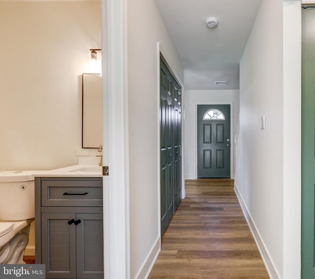 hall with visible vents, dark wood finished floors, and baseboards