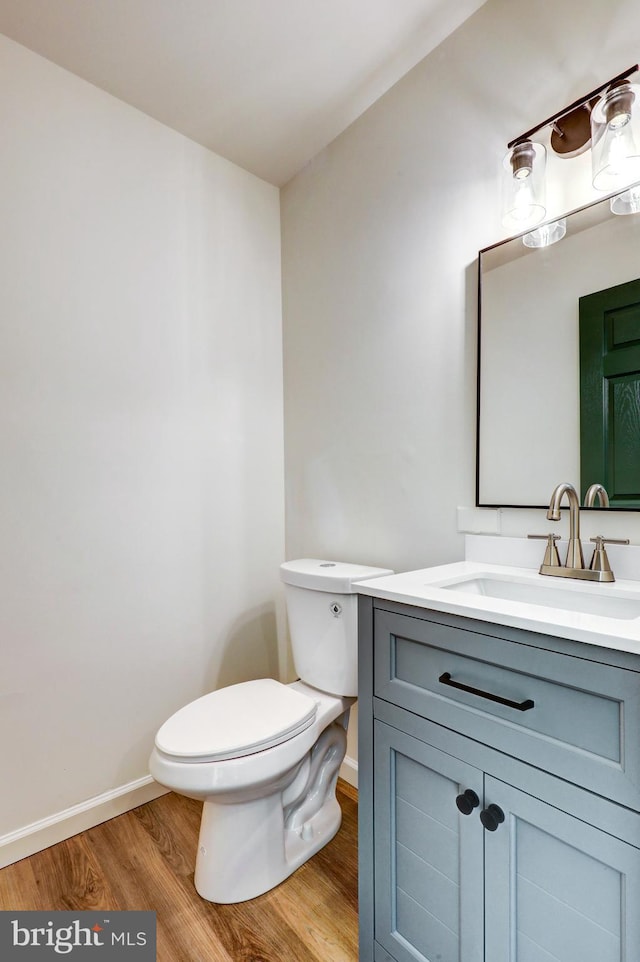 bathroom with baseboards, vanity, toilet, and wood finished floors