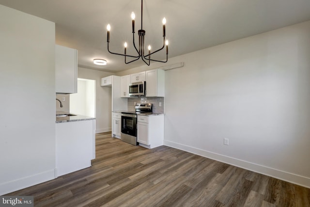 kitchen with dark wood-style floors, white cabinetry, tasteful backsplash, a notable chandelier, and stainless steel appliances