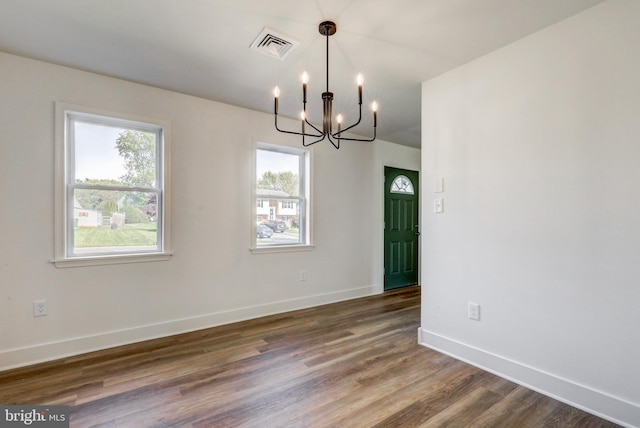 unfurnished dining area featuring an inviting chandelier, plenty of natural light, wood finished floors, and visible vents
