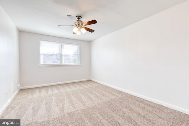 carpeted empty room with a ceiling fan and baseboards
