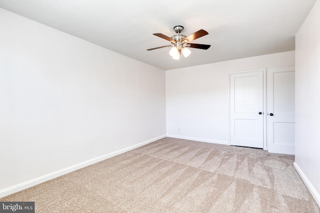 carpeted empty room featuring a ceiling fan and baseboards