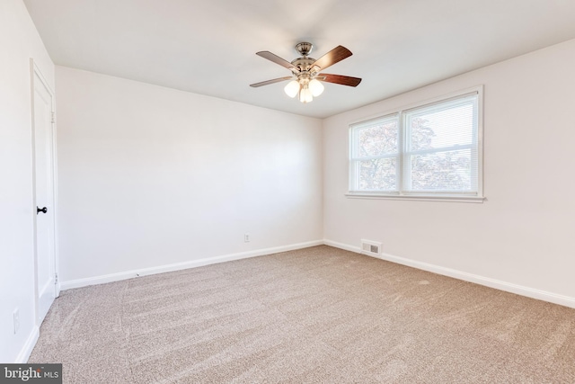 empty room featuring baseboards, ceiling fan, light colored carpet, and visible vents