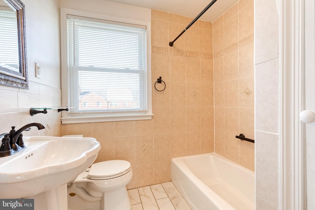 full bathroom featuring toilet, tile walls, shower / tub combination, and a sink