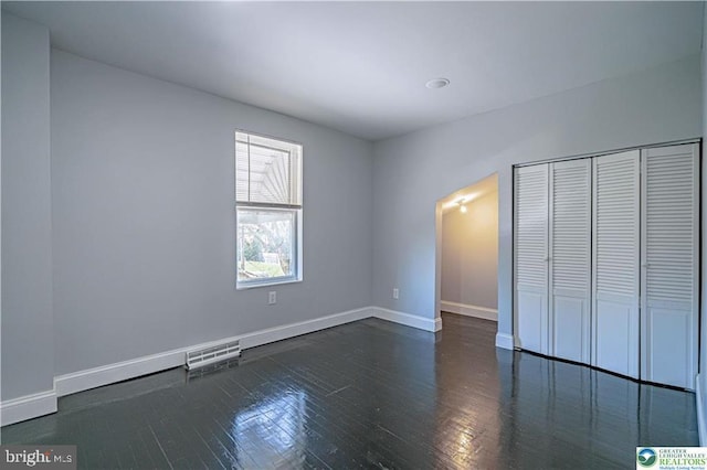 unfurnished bedroom featuring baseboards, visible vents, wood finished floors, and a closet