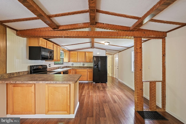 kitchen with hardwood / wood-style flooring, baseboards, black appliances, a peninsula, and vaulted ceiling with beams