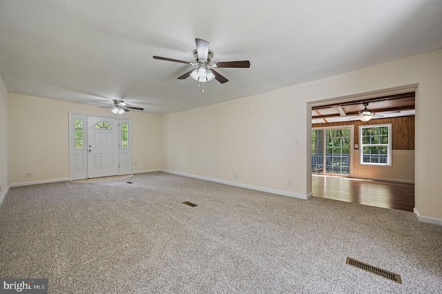 unfurnished living room featuring carpet floors, a ceiling fan, visible vents, and a wealth of natural light