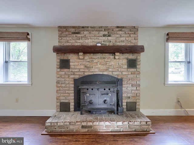 room details with baseboards, a wood stove, visible vents, and wood finished floors