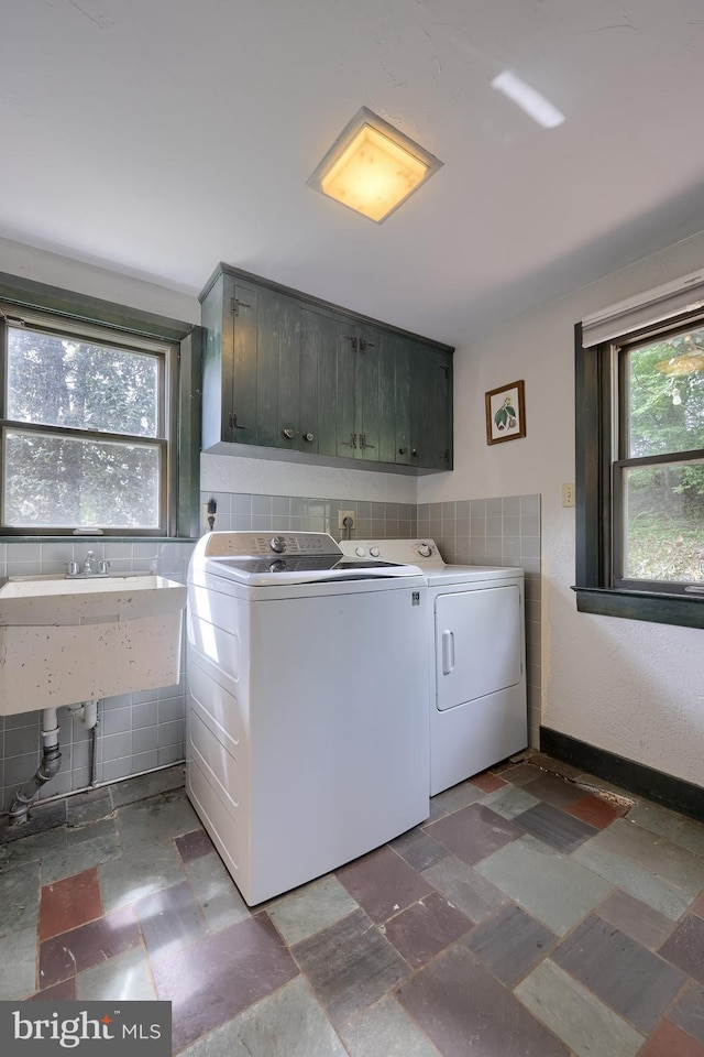 washroom featuring washing machine and clothes dryer, plenty of natural light, a sink, and cabinet space