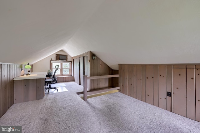 carpeted office space featuring lofted ceiling and wooden walls
