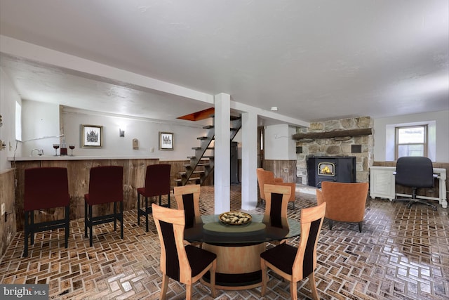 dining room with stairs, a bar, a fireplace, and brick floor