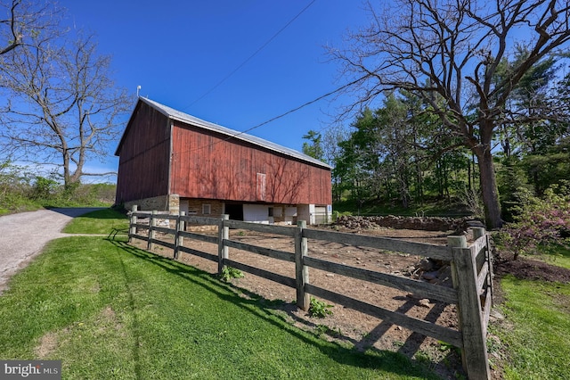 view of barn featuring fence and a lawn