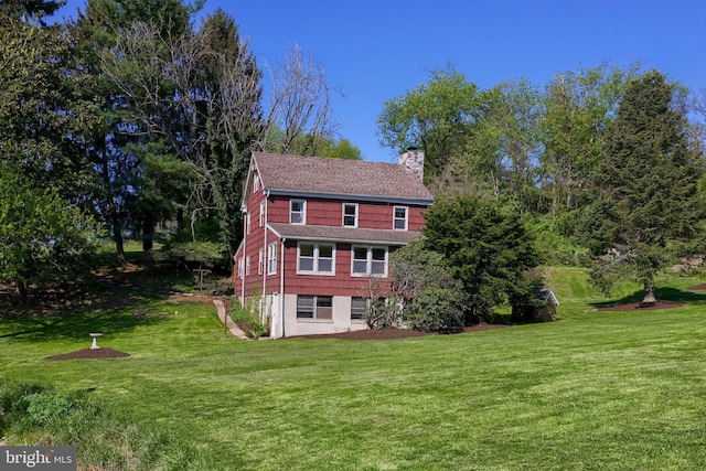view of side of home with a yard and a chimney