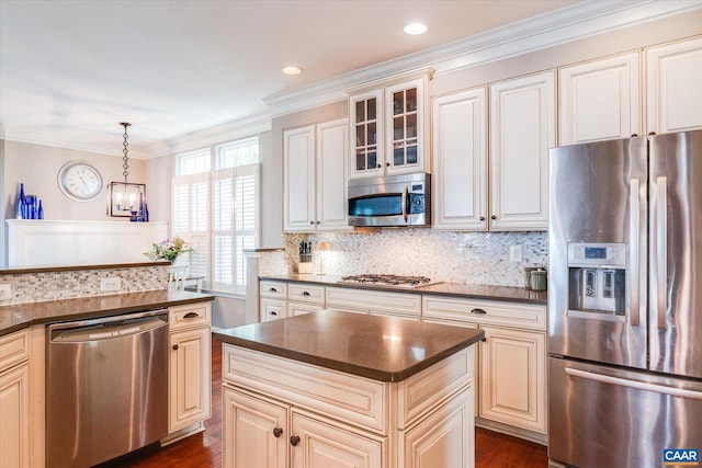 kitchen with dark countertops, appliances with stainless steel finishes, tasteful backsplash, and cream cabinetry