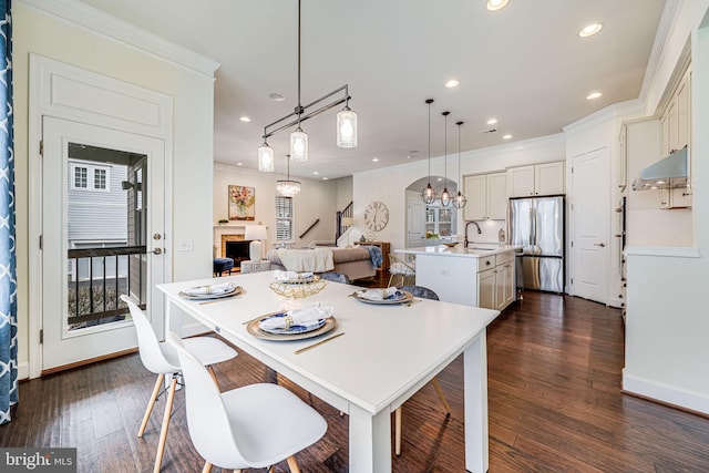 dining room with ornamental molding, a fireplace, recessed lighting, dark wood-style flooring, and a chandelier