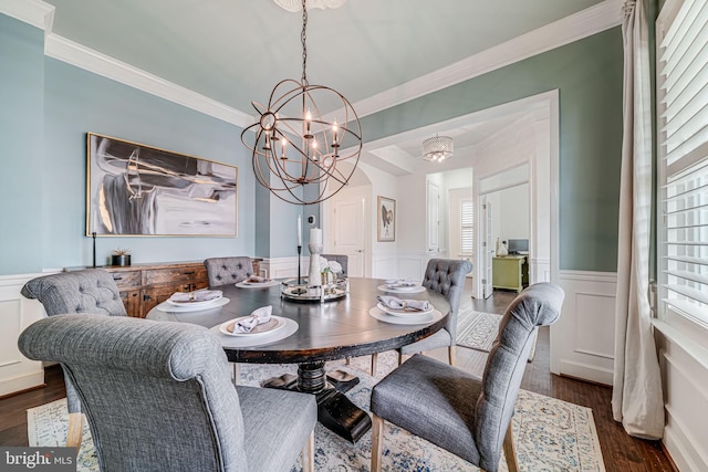 dining area featuring healthy amount of natural light, wainscoting, ornamental molding, a chandelier, and dark wood-style flooring