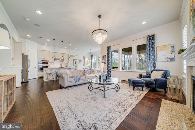 living room with a fireplace, ornamental molding, a chandelier, dark wood-type flooring, and baseboards